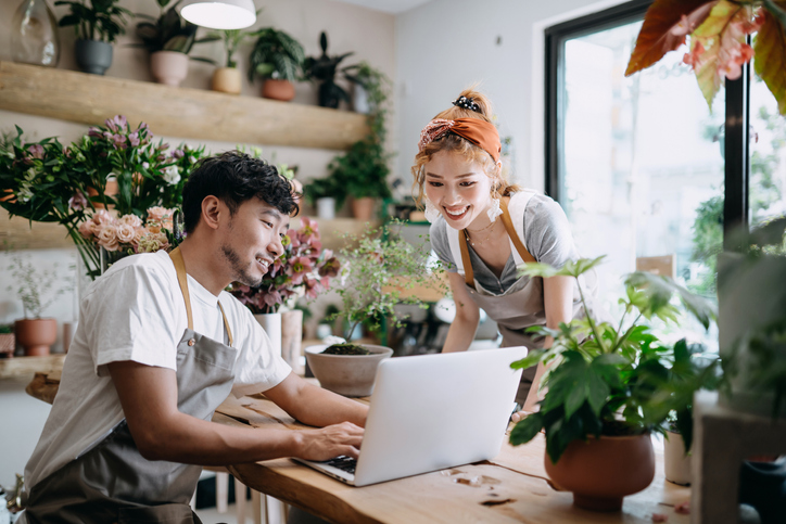 two business owners of flower shop looking at laptop